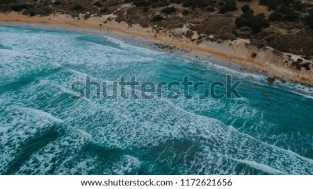 Beautiful aerial drone view of sandy beach and turquoise mediterranean sea with big waves and white foam. Evening, dusk