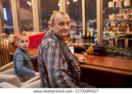 Grandfather and grandson sit at counter in cafe on holiday.