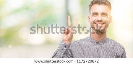 Young hipster man showing and pointing up with fingers number two while smiling confident and happy.