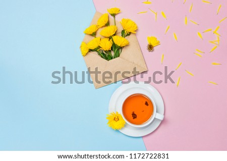 Opened envelope with yellow chrysanthemums, cup of tea on blue pink background top view flat lay. Concept Good morning, Greeting card, floral background womens day 8 of march, mothers day