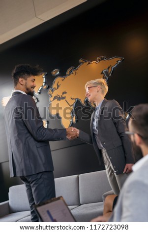 Businessman and business woman shaking hands after achieving agreement and signing contract. Focus on the woman