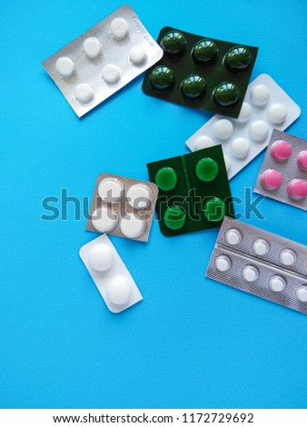 Different pills on blue background. Plate with pills of different colors. Means for treating the disease. The recipe from the attending physician