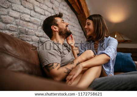 Cropped shot of a happy young couple cuddling in the living room Royalty-Free Stock Photo #1172758621