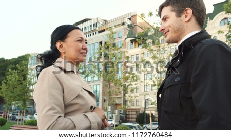 The camera takes people from the bottom view. A man with a woman is talking about something. Then the man stretches out his hand to the woman. They shake hands. They look very serious