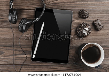 Cup of coffee, tablet, headphones and sweet biscuits on wooden office desktop, top view