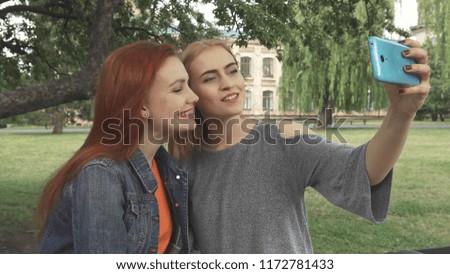 Friends posing and taking selfies. Then discuss the photos. Women have a rest in park near university
