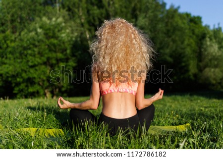 Photo from back of female athlete practicing yoga on rug