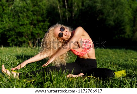Photo of young curly woman in sunglasses lying on rug in park