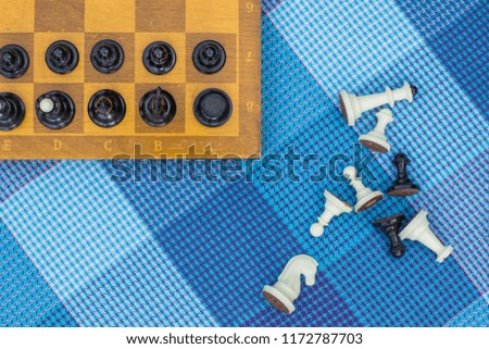 creative foreshortening from above chess concept with wooden desk with black and white figures on game space and lay near on carpet background texture, copy space for your text