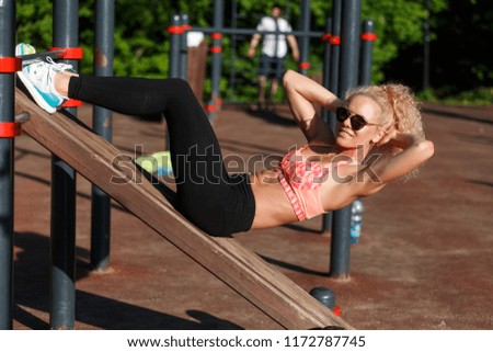Photo of sports woman wearing sunglasses training press in park