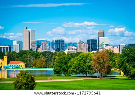 Green space city view in Denver Colorado downtown skyline rising behind green city park tree line with Rocky Mountain background the mile high city