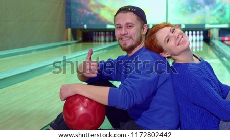 Boy and girl sitting on the floor at the bowling alley