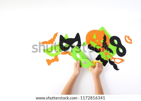 Halloween. The  masks from paper on a white background which are cut out. Children's hands.