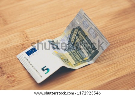A 5 euro banknote on a wooden table top.  This image can be used as a money background 