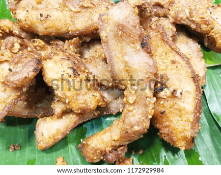 Close up fried sliced pork on green banana leaf, Thai street food