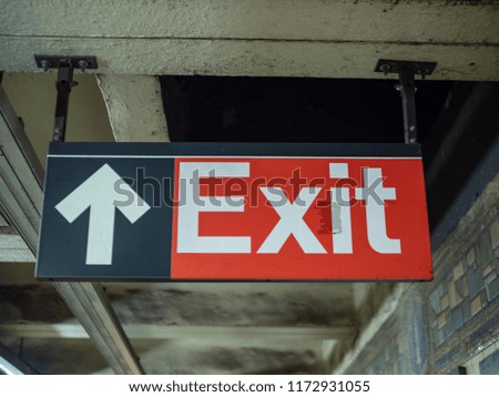 A red exit sign with arrow hanging in underground subway station