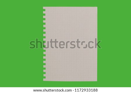 sheet of white paper from notebook lying isolated on a green background. free space for advertising text