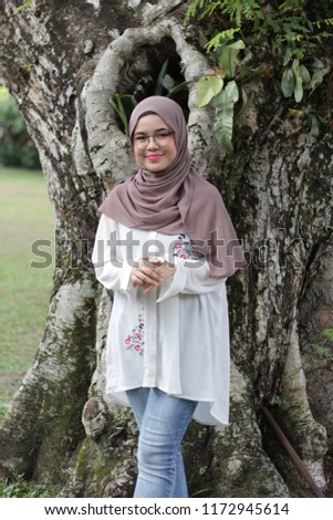 Portraiture of a young asian girl  wearing hijab outdoor photoshoot at a park by the tree. Relax at park