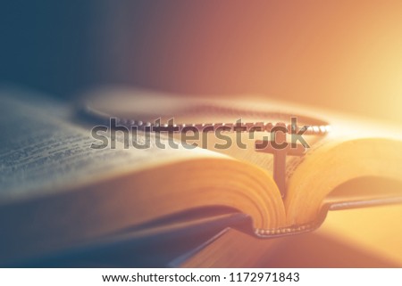 Closeup of wooden Christian cross necklace next to holy Bible Royalty-Free Stock Photo #1172971843