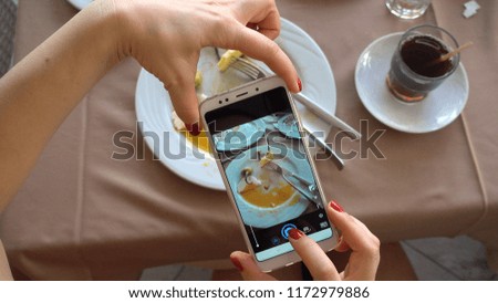 The process of photographing a smartphone. The girl is making a photo for the social network. Plates with the remains of food. Breakfast at the Turkish hotel.