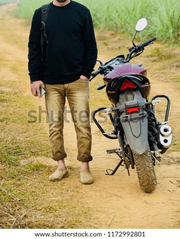Man wearing faded jeans standing beside a bike unique photo