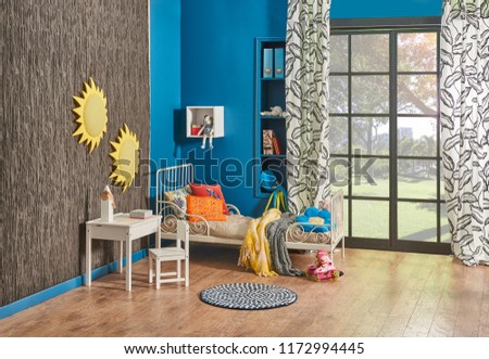 Decorative child room concept blue wall and brown panel on the wall. White child bed in front of the window. Garden view and sun pattern room.
