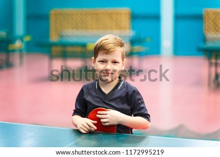 the child is holding a racket for table tennis indoors