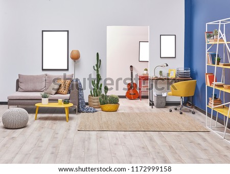White blue wall concept living room style. Grey sofa and frame decoration. working table in the back and yellow bookshelf.