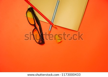 Red and blue pencils, black glasses and yellow sharpener isolated on pink background