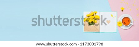 Opened envelope with yellow chrysanthemums, cup of tea and notebook on blue pink background top view flat lay. Concept Good morning, Greeting card womens day 8 of march mothers day Long banner