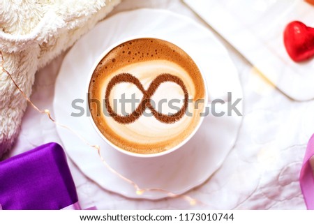 a cup of cappuccino coffee with a symbol of the symbol of infinity on milk foam