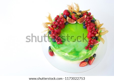 Cake with whipped green cream, decorated with fresh strawberries, blueberries, figs and physalis on white background. Picture for a menu or a confectionery catalog. Top view.