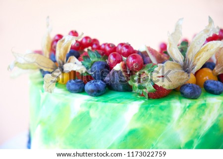 Cake with whipped green cream, decorated with fresh strawberries, blueberries, figs and physalis on white background. Picture for a menu or a confectionery catalog. Close up.