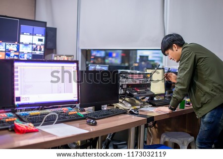 Behind the televised broadcast in the control room, live in the control room. Producer looking at the chart list on the table. Royalty-Free Stock Photo #1173032119