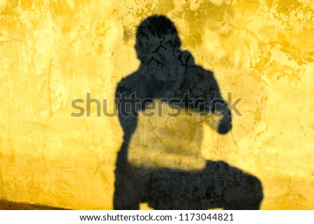 yellow and black human reflection on concrete wall surface in morning sunlight