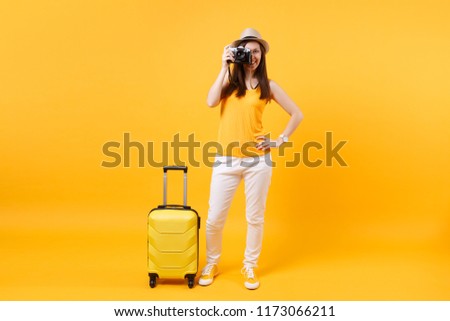 Tourist woman in summer casual clothes with suitcase, retro vintage photo camera isolated on yellow orange background. Passenger traveling abroad to travel on weekends getaway. Air flight concept