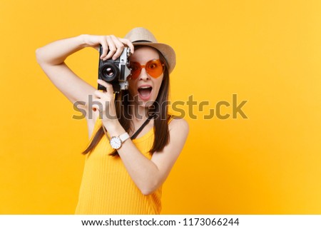 Tourist woman in summer casual clothes, hat take picture on retro vintage photo camera isolated on yellow background. Girl traveling abroad to travel on weekends getaway. Air flight journey concept