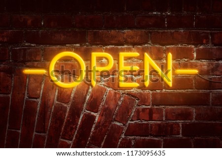 Neon inscription Open against the background of the old brick wall. Advertising. Business