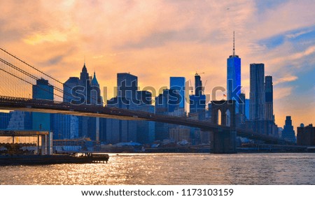 sunset on iconic manhattan modern architecture skyline with brooklyn bridge in Manhattan New York city with warm colors and cloudy orange sky