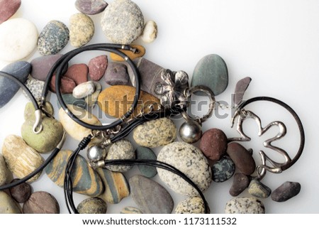 exclusive female jewelry, leather plus metal, lying on stones, on white background