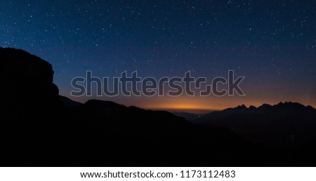 Early morning panorama viewed from Grossglockner mountain pass, with visible multitude of stars on the sky above the mountains. Sun is slowly starting to rise and glow is visble.