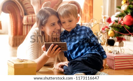 Smiling mother with her little son watching cartoons on Christmas morning