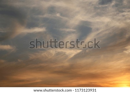 Sunset beautiful background for soaring clouds in the blue sky streams of warm light are carried by the wind across the horizon