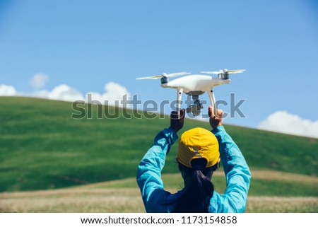 Woman photographer with drone in high altitude grassland