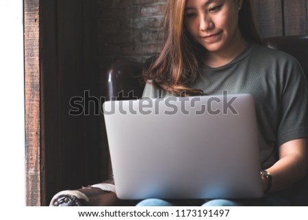 Closeup image of a woman working and typing on laptop while sitting on sofa