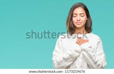 Young beautiful arab woman wearing winter sweater over isolated background smiling with hands on chest with closed eyes and grateful gesture on face. Health concept. Royalty-Free Stock Photo #1173219676