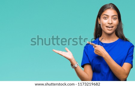 Young beautiful arab woman over isolated background amazed and smiling to the camera while presenting with hand and pointing with finger.