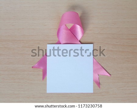 Breast cancer awareness concept : Pink ribbon symbol of breast cancer, doctor Stethoscope on wooden background.  Blank paper with copy space for your text.