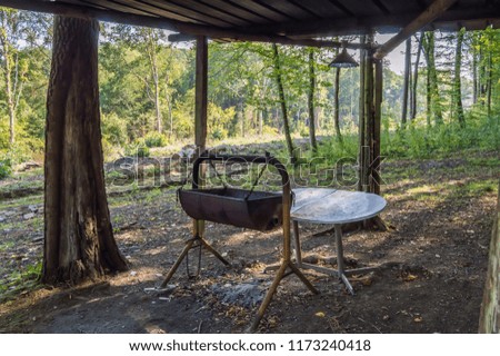 Hanging barbecue made with an old barrel under a wooden roof in the forest