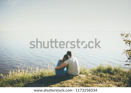 couple is hugging sitting to the sun looking to the sea